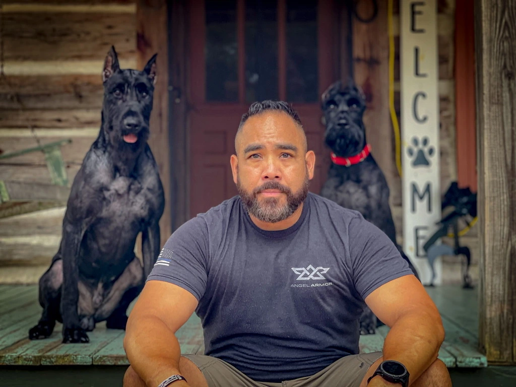Joseph Garcia seated in front of two Giant Schnauzers