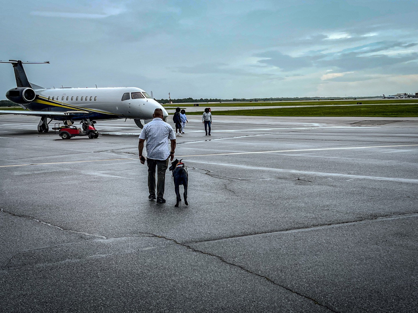 A K1K9 walking with the Senior Handler to a private aircraft at dusk